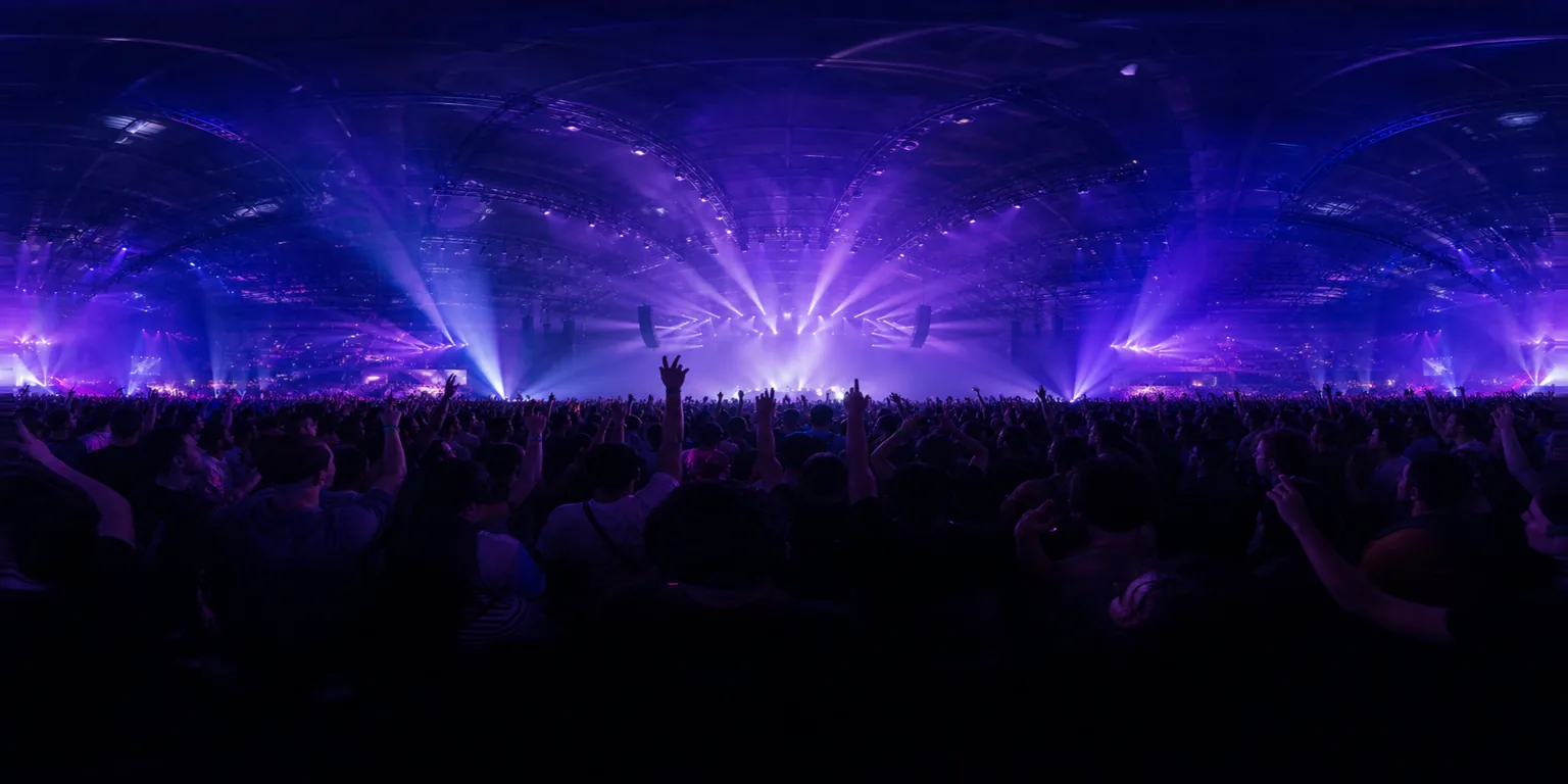 Concert stage seen from the audience with light beams and raised silhouettes